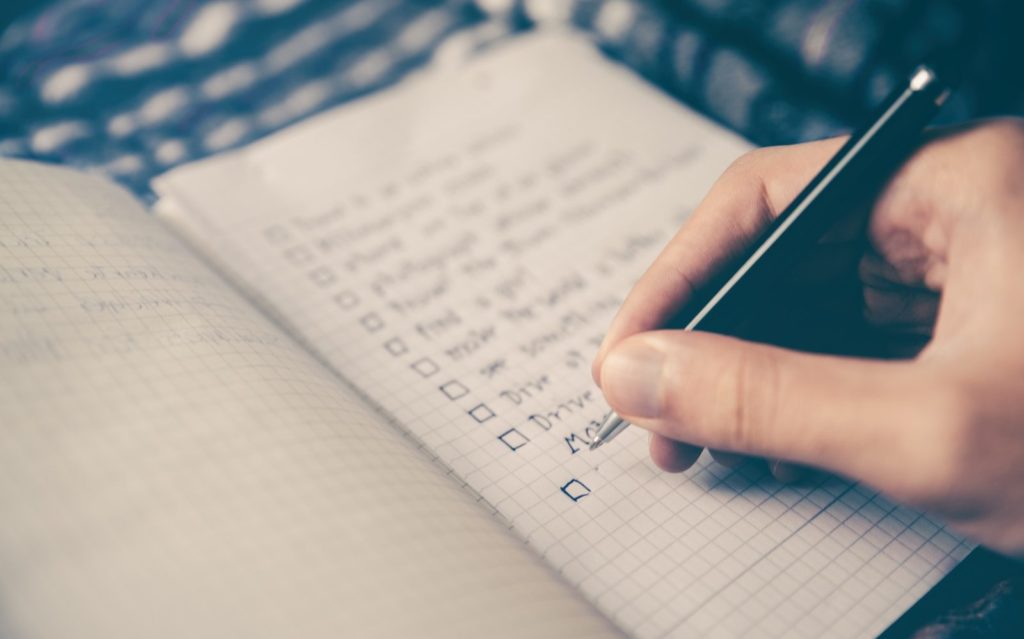 person writing bucket list on book